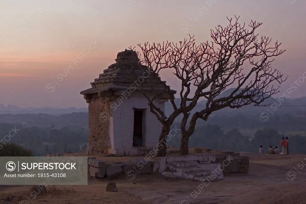 India, tree by stone hut in twilight