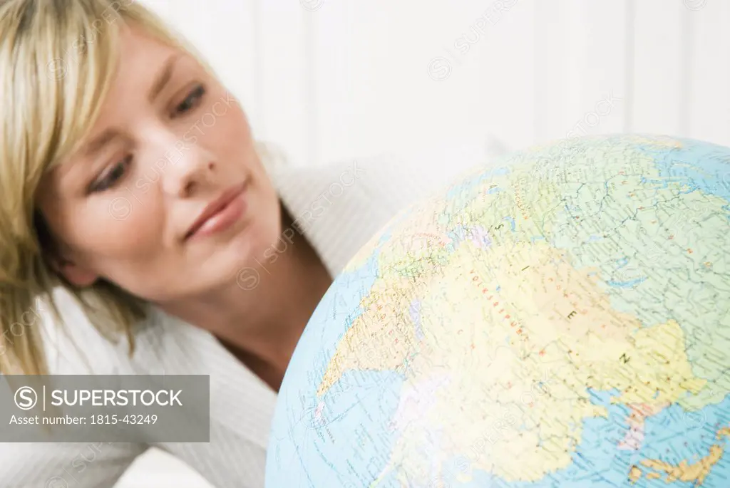 Young businesswoman looking at globe, portrait, close-up