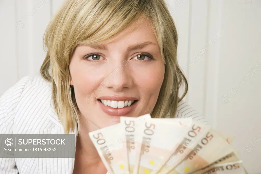 Woman holding 50 Euro notes, smiling, portrait