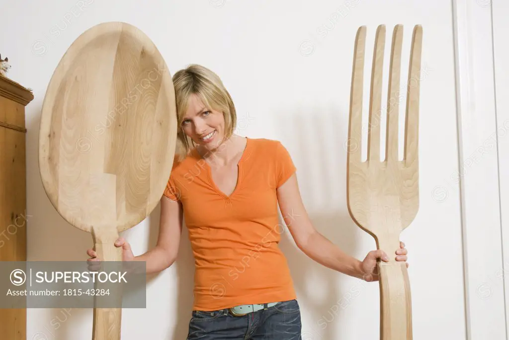 Woman holding giant cutlery in hands, close-up