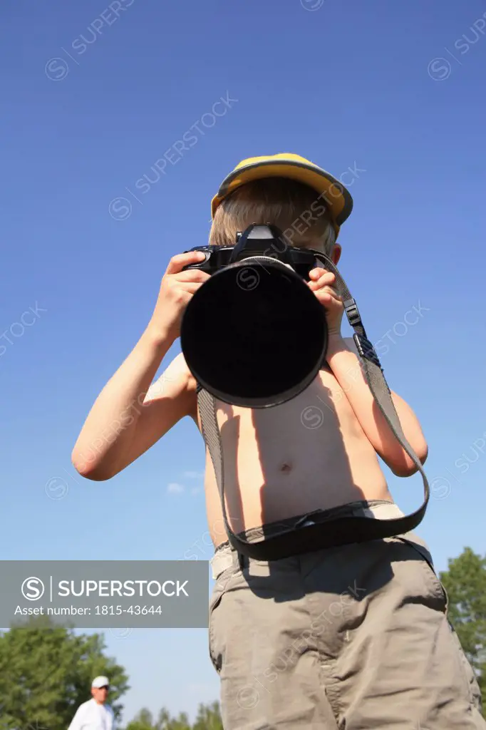 Boy (10-12) holding camera, front view