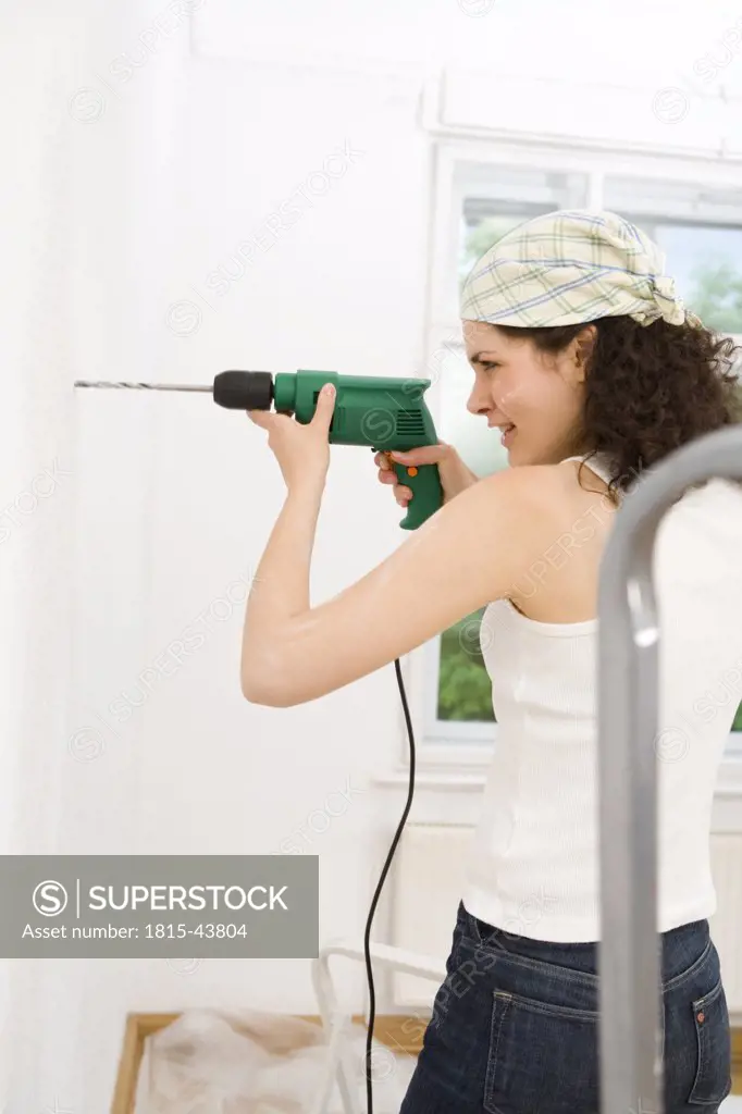 Young woman using drill
