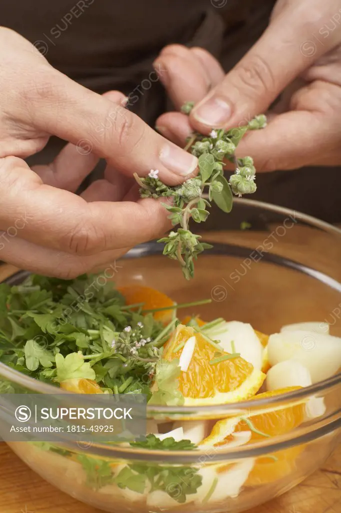 Putting herbs into bowl, close-up