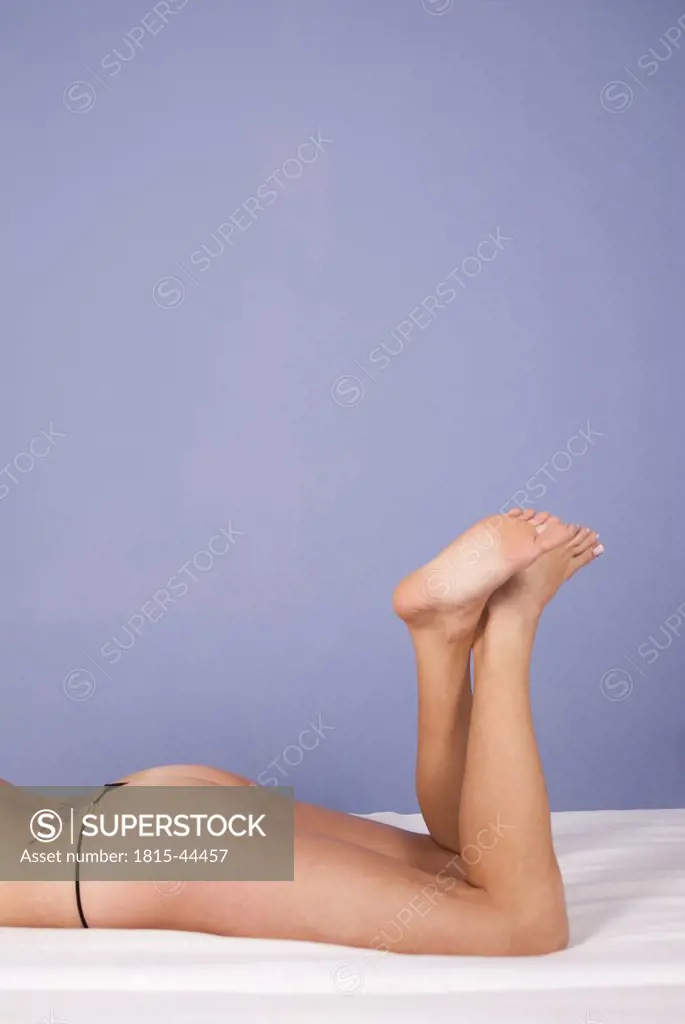 Woman lying on bed, feet crossed