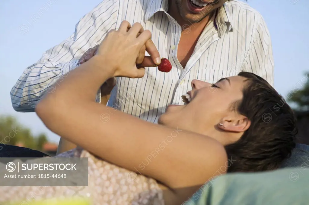 Young couple eating strawberries, outdoors
