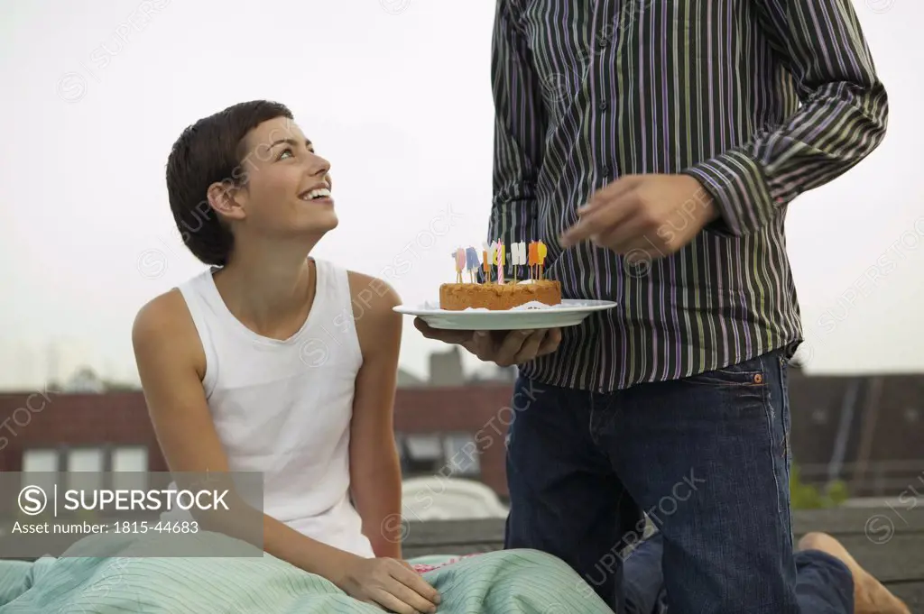 Young man giving birthday cake to woman