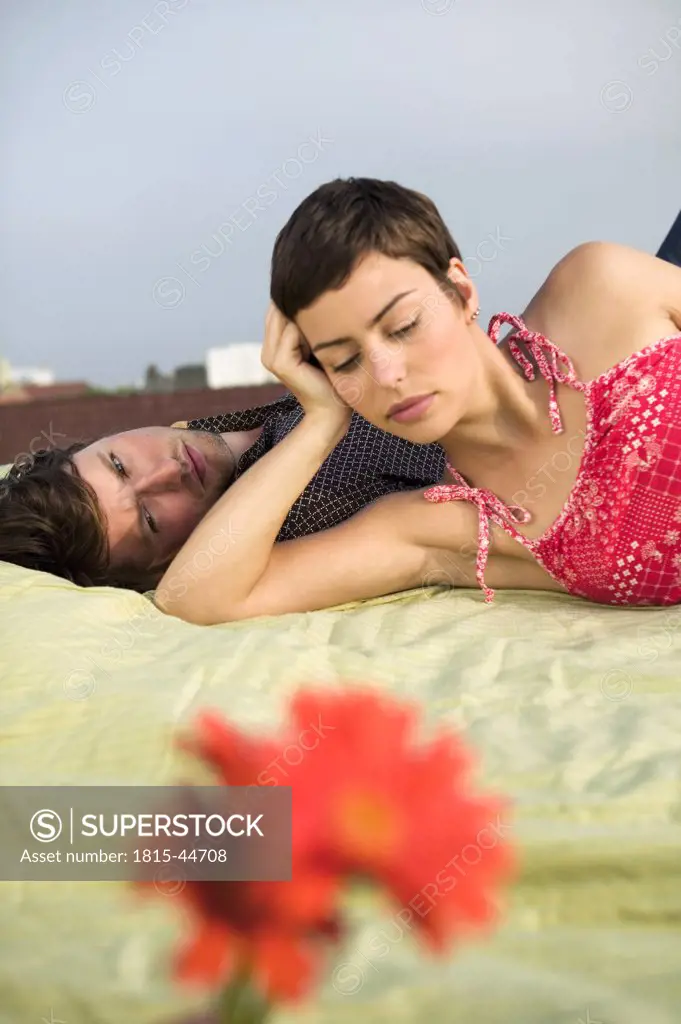Couple relaxing on blanket, flowers in foreground