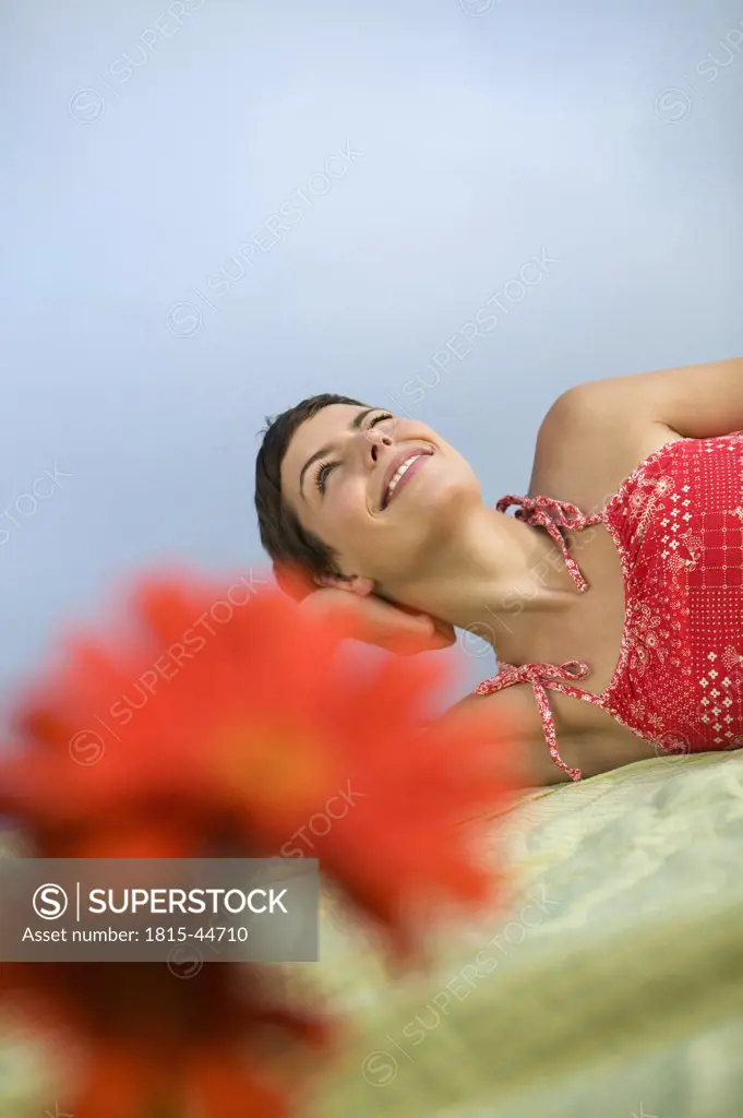 Woman lying on blanket, smiling, flowers in foreground