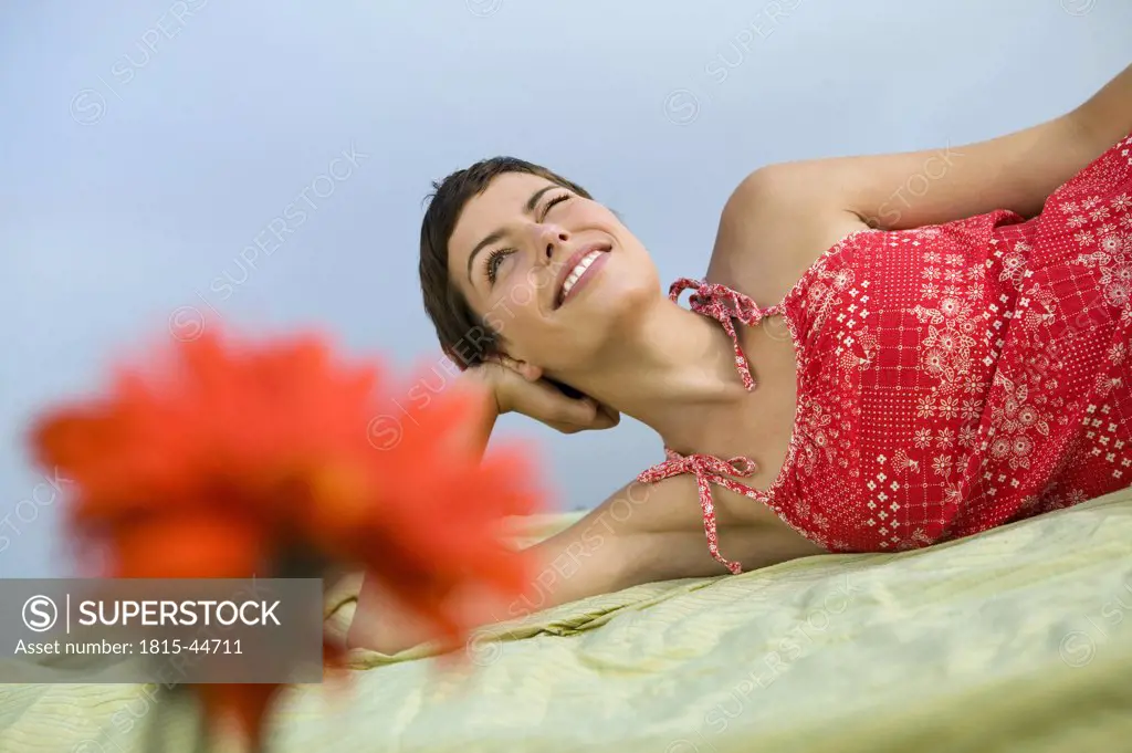 Woman lying on blanket, smiling, flowers in foreground