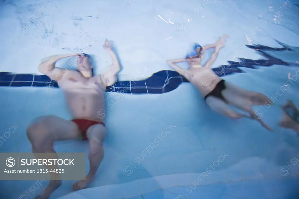 Two man in pool, under water