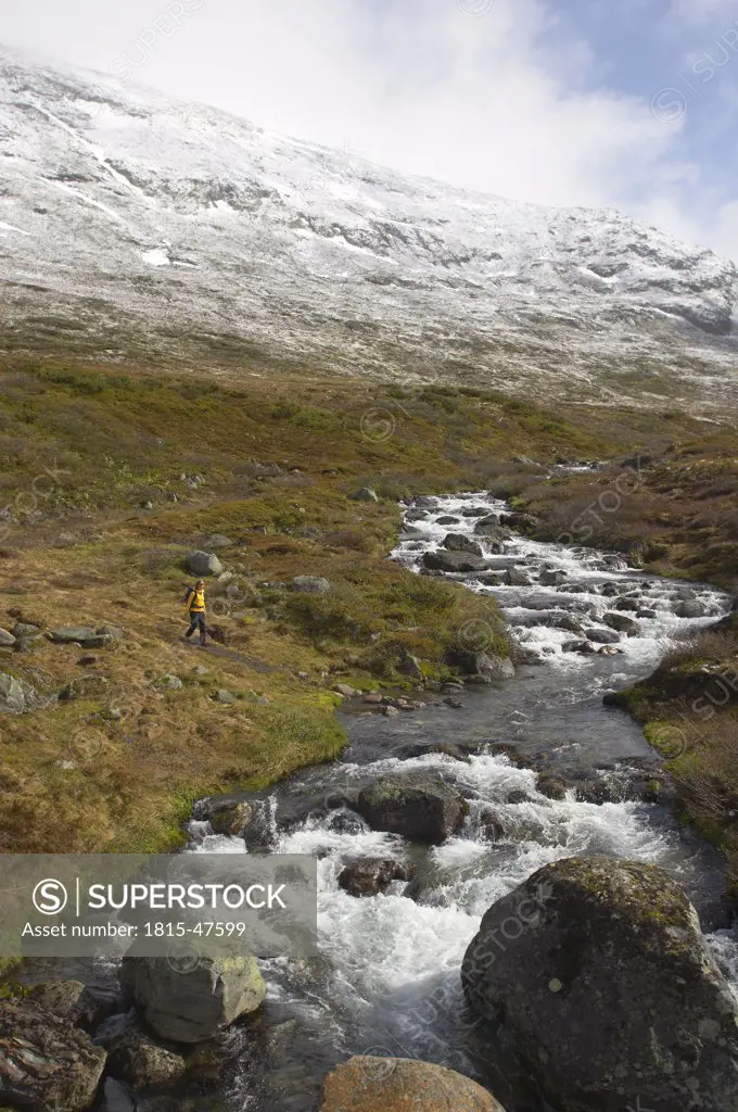 Norway, Laerdal, Woman hiking, brook in foreground