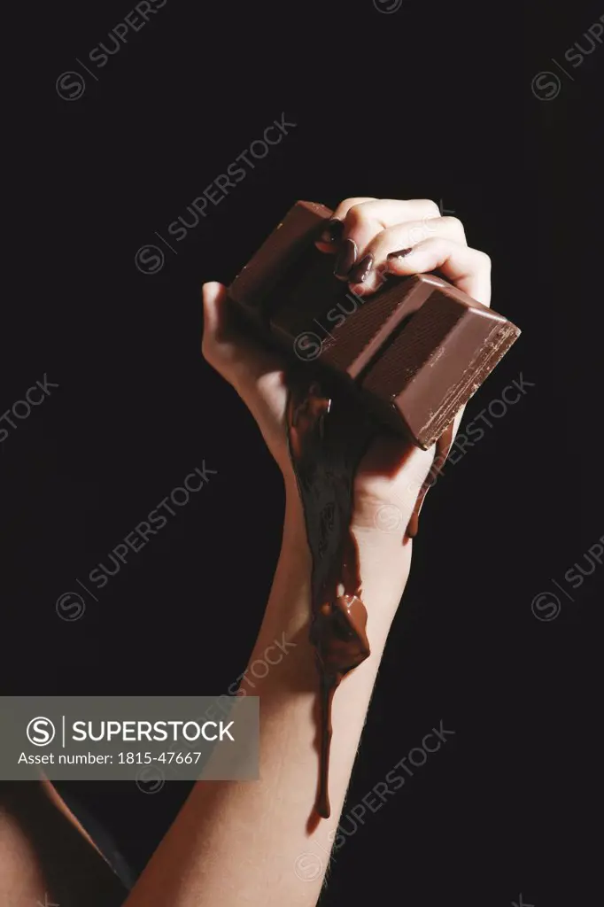 Female hand holding melting chocolate bar, close-up