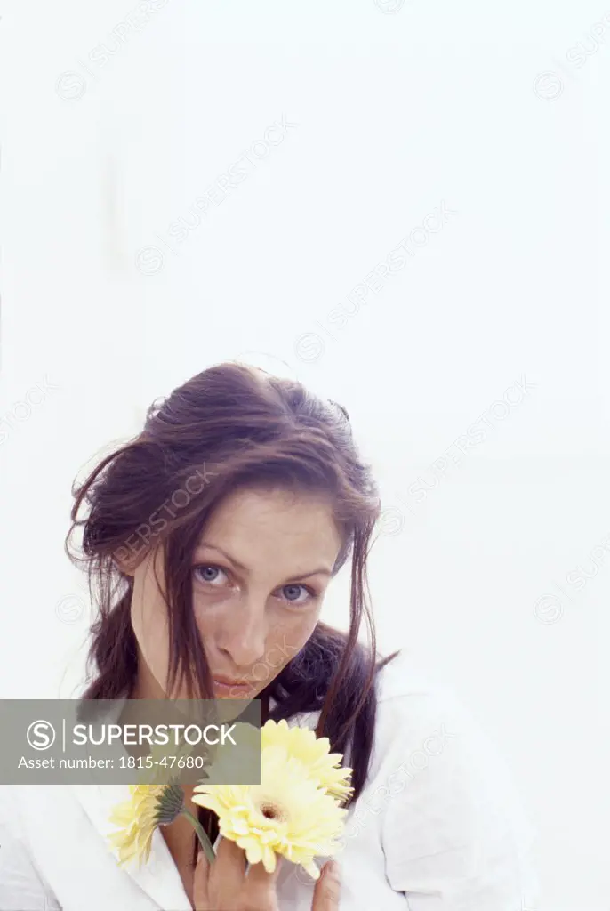 Young woman holding flowers, smiling, portrait