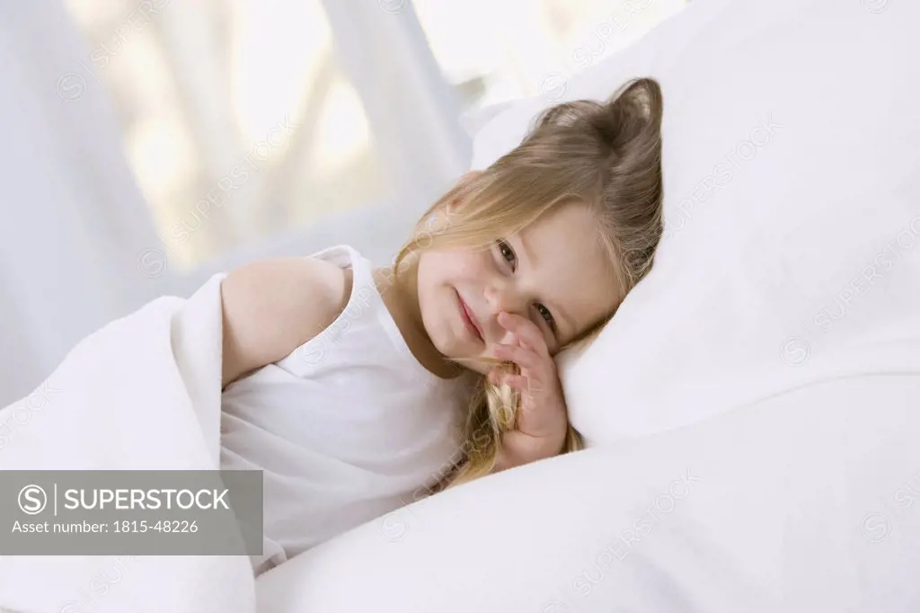Little girl (3-4) relaxing in bed, portrait