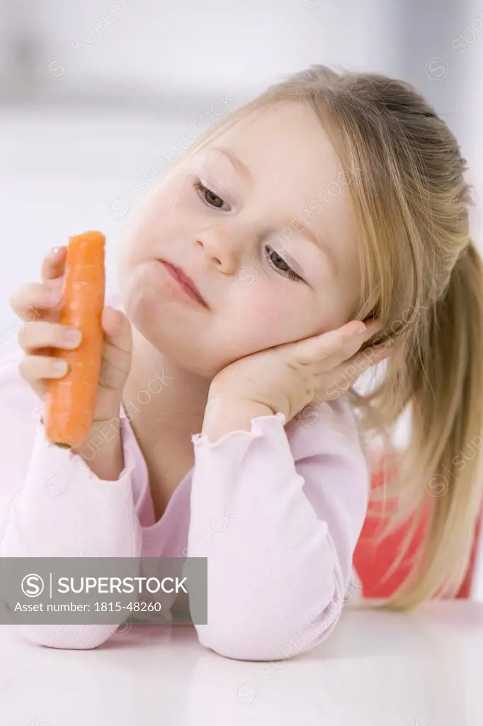 Little girl (3-4) holding a carrot, portrait