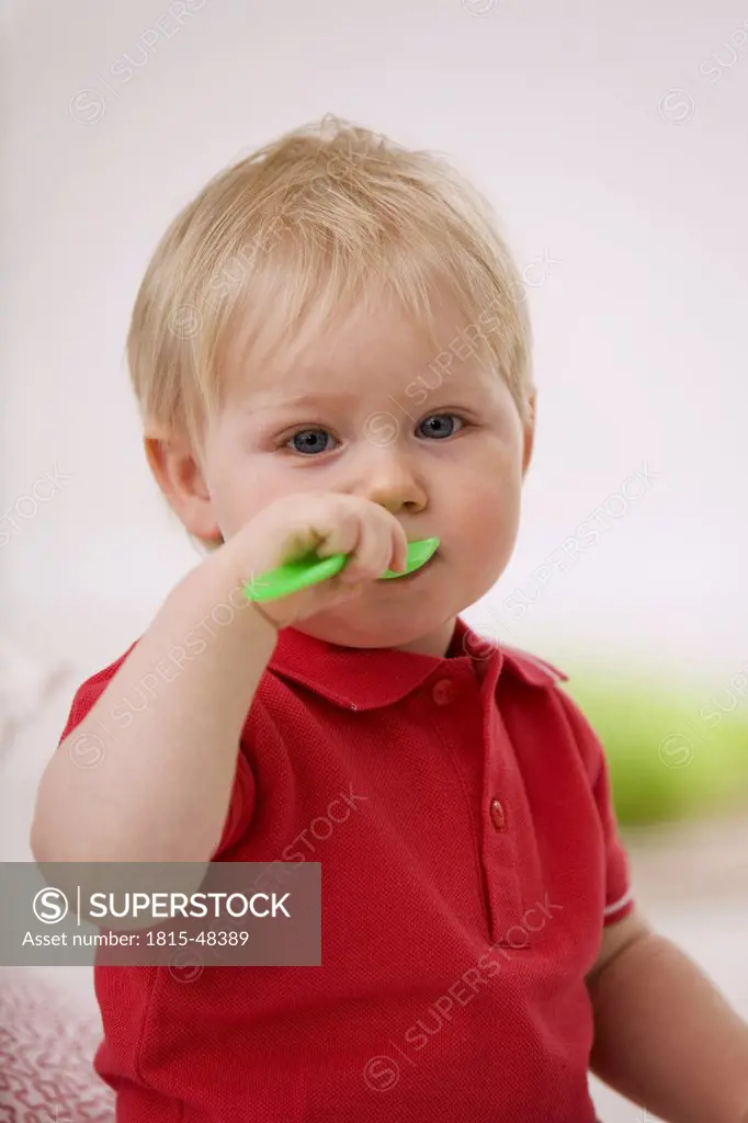 Baby boy (1-2) playing with plastic spoon
