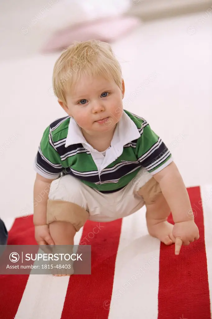 Baby boy (1-2) squatting on bright carpet