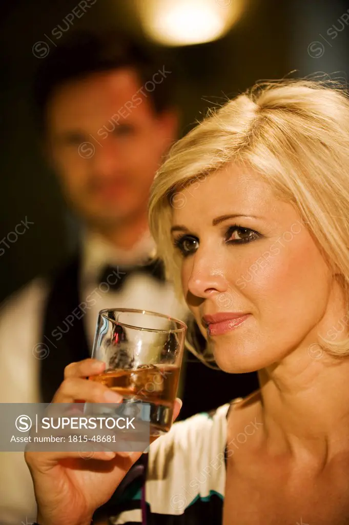 Young woman in bar holding glass, portrait