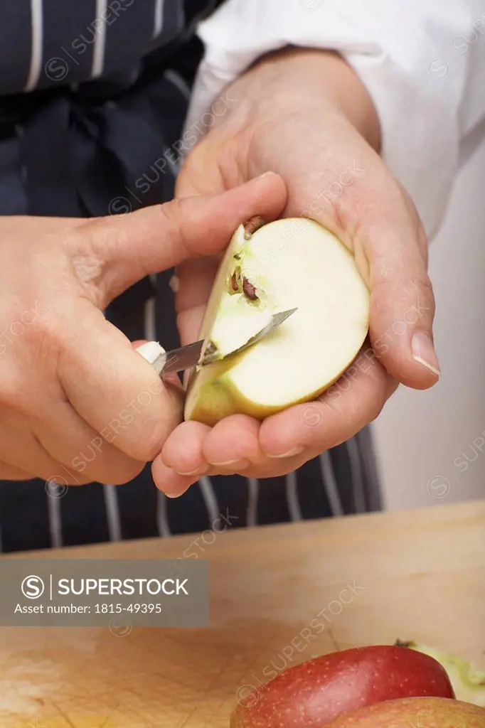 Person coring an apple with knife, close_up
