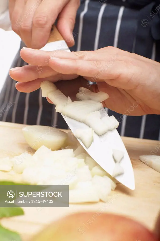 Person holding knife with onion pieces, close_up