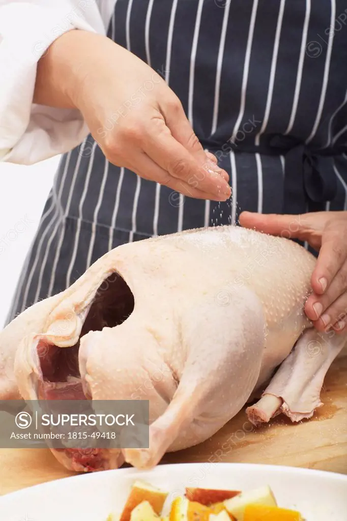 Person salting roast goose, close_up