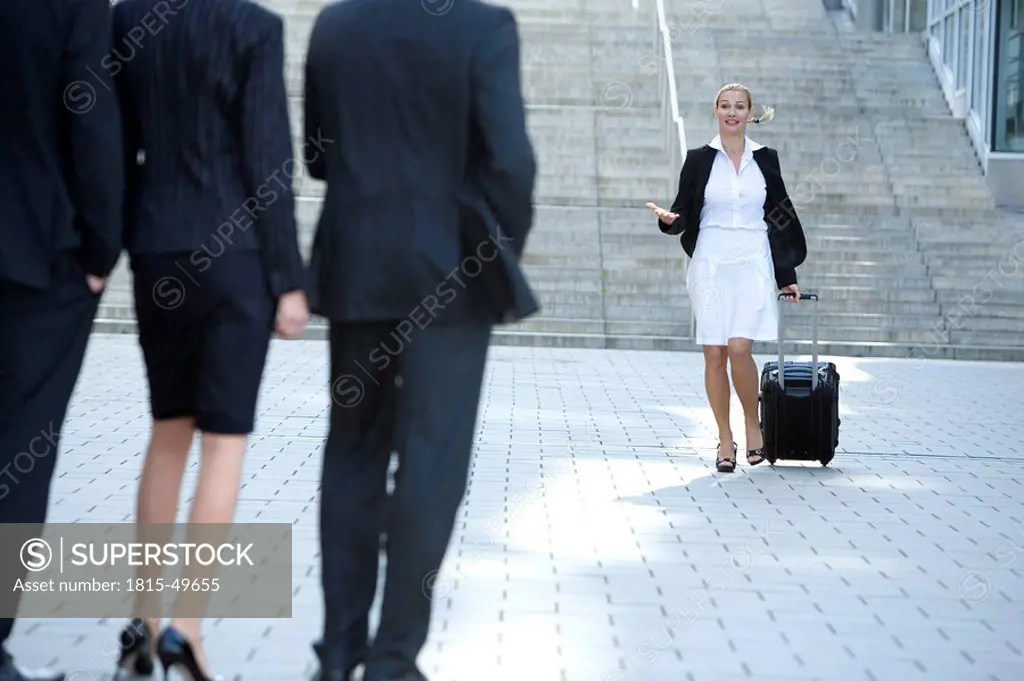 Germany, Baden_Württemberg, Stuttgart, Businesspeople waiting, woman walking with case