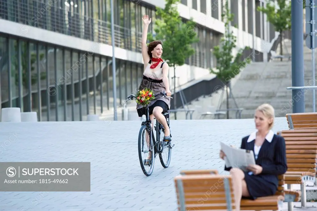 Germany, Baden_Württemberg, Stuttgart, Woman cycling, another woman reading newspaper