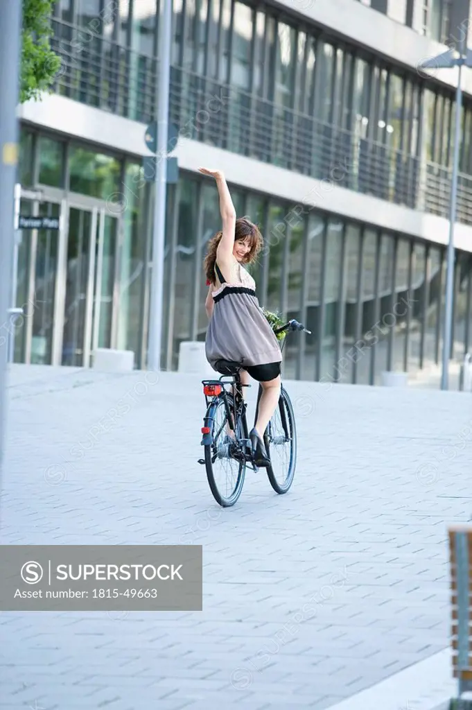 Germany, Baden_Württemberg, Stuttgart, young woman cycling in town
