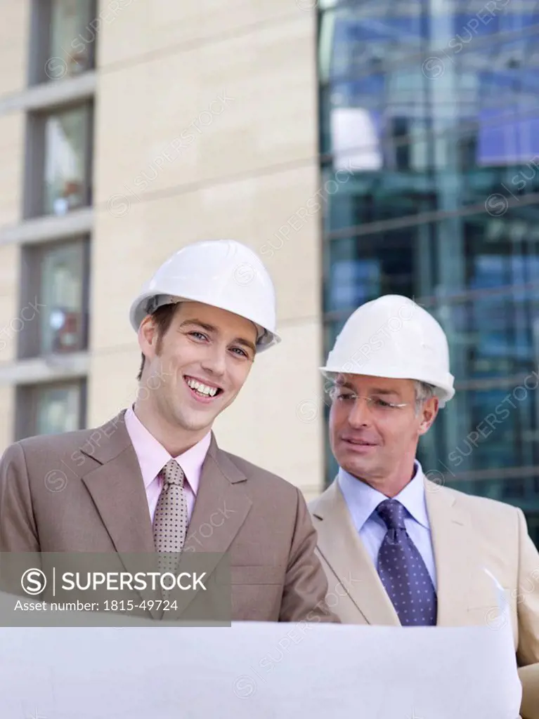Germany, Baden_Württemberg, Stuttgart, two businessmen with hard hats discussing building plan