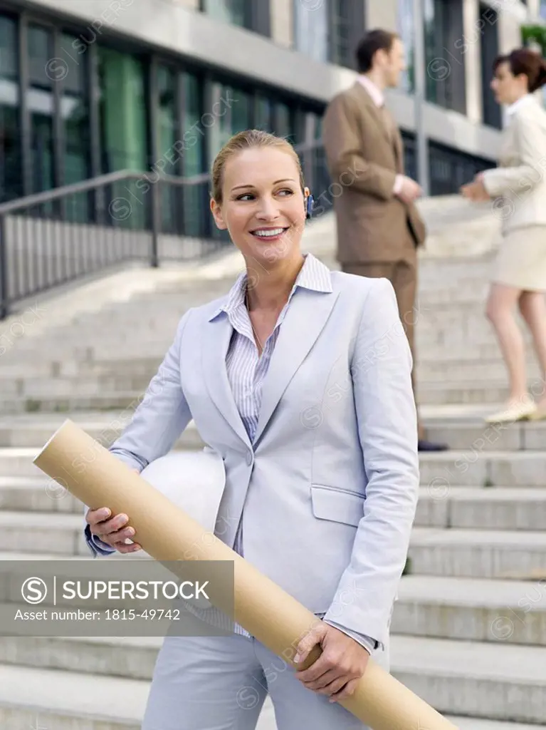 Germany, Baden_Württemberg, Stuttgart, Businesswoman with roll, businesspeople in background