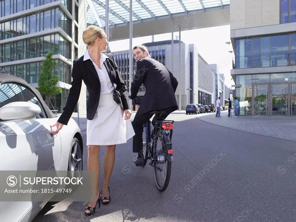 Germany, Baden_Württemberg, Stuttgart, Businessman cycling, woman at sports car