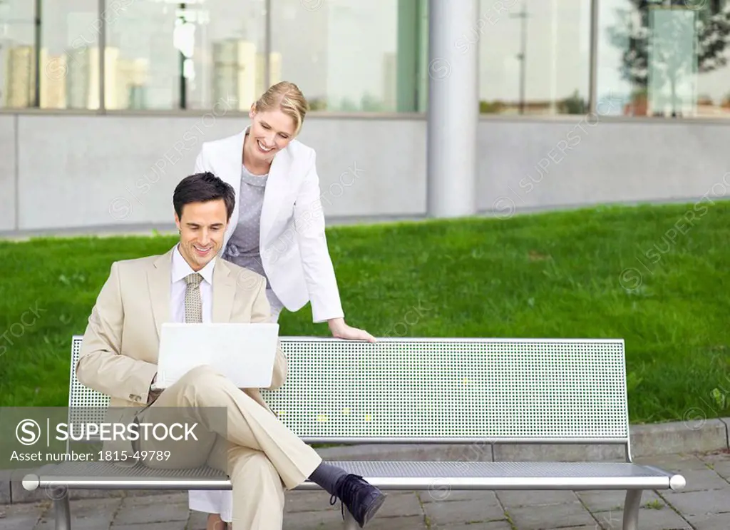 Germany, Baden_Württemberg, Stuttgart, Two businesspeople with laptop at park bench