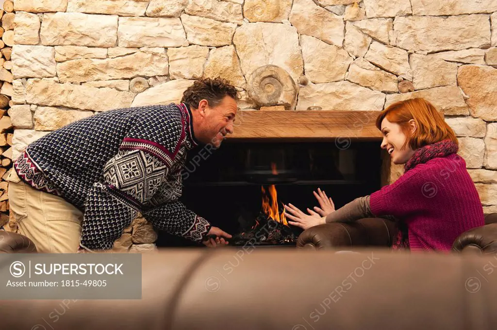 Couple in living room by fireside, having a good time