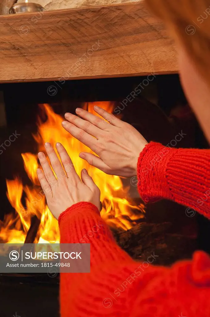 Woamn warming his hands at open fire, close_up