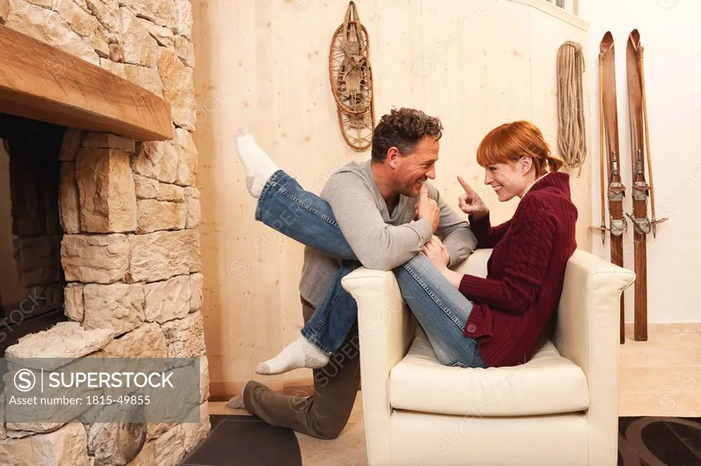 Couple sitting by fireside, fooling about
