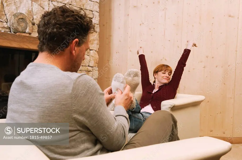 Couple relaxing in living room, man massaging woman´s foot