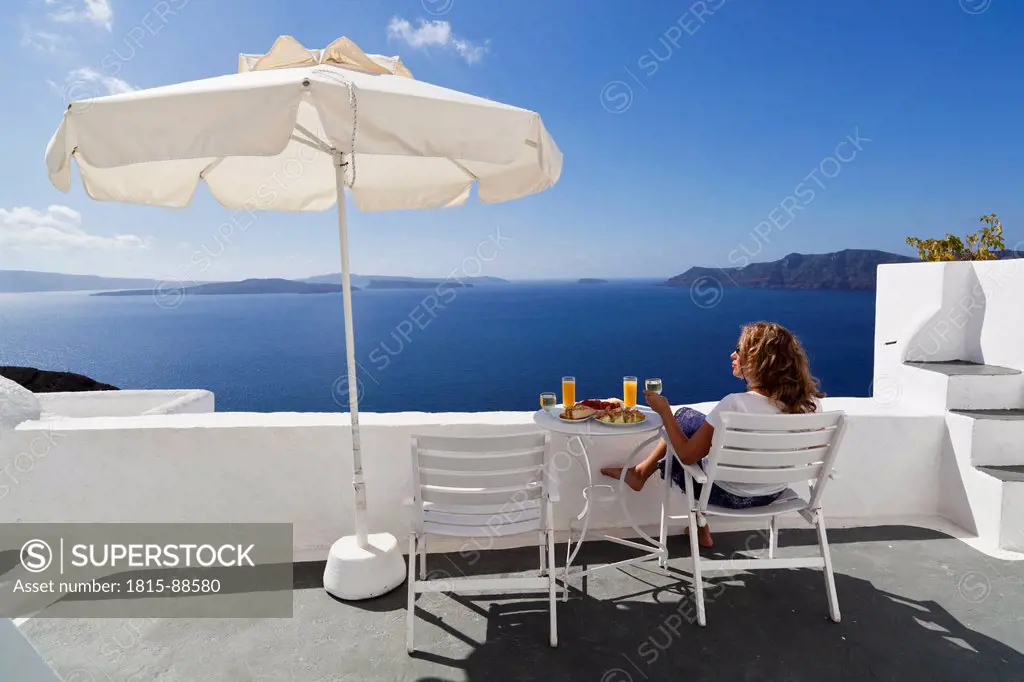 Greece, Cyclades,Thira, Santorini, Oia, Mature woman relaxing with blue sea in background