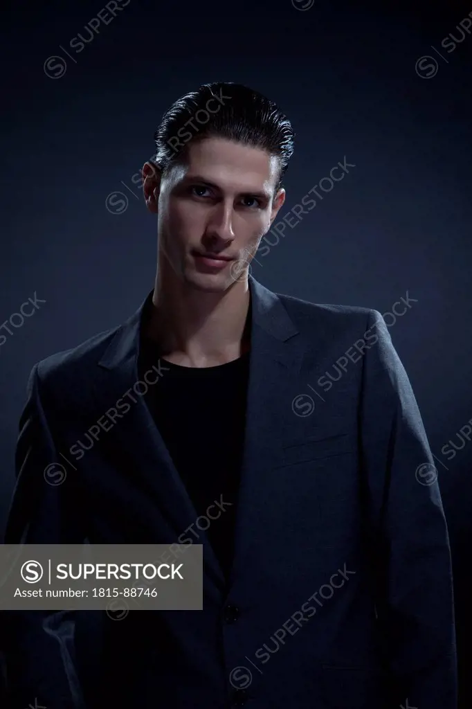 Young man against black background, portrait