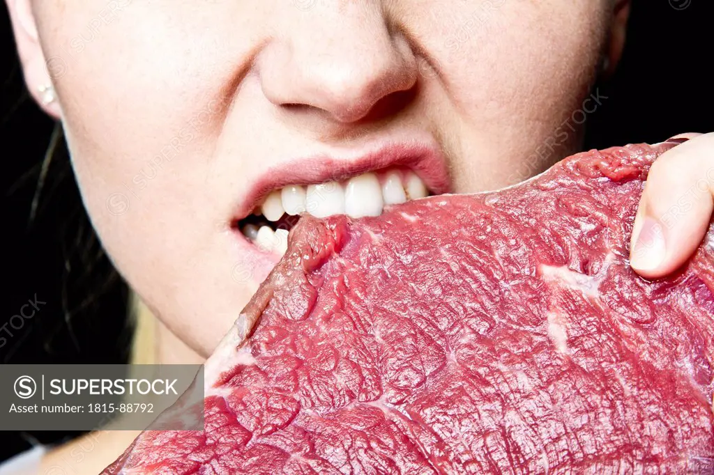 Young woman eating raw meat, portrait