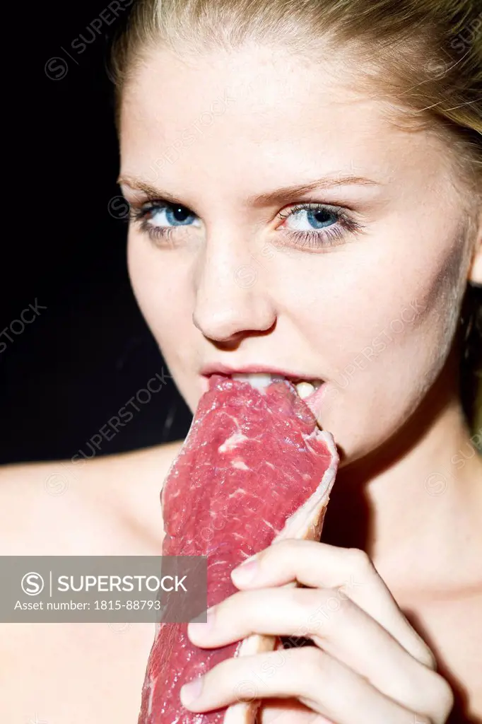 Young woman eating raw meat, portrait