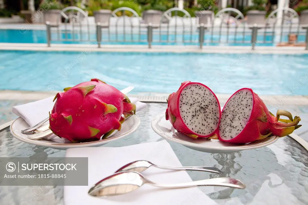 Malaysia, Kuala Lumpur, Dragon fruit in plate with pool in background pof 5 star hotel