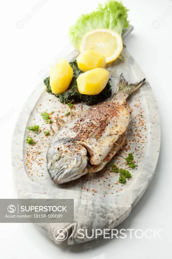 Garnished gilthead bream in plate on white background