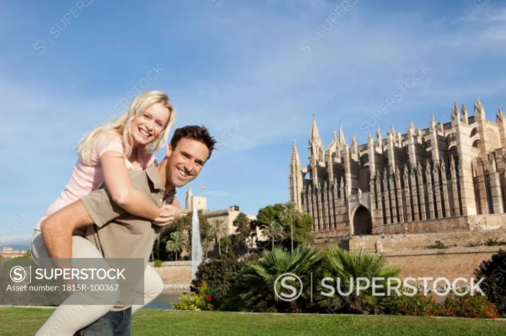 Spain, Mallorca, Palma, Couple smiling with St Maria Cathedral in background, portrait