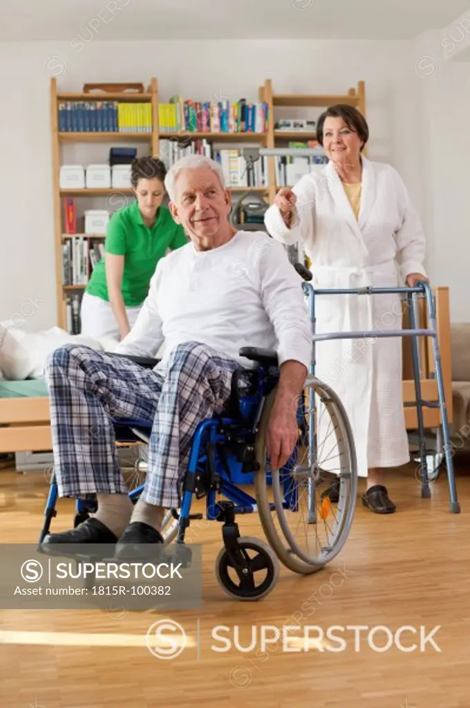 Germany, Leipzig, Senior man sitting on wheelchair, woman with walking frame