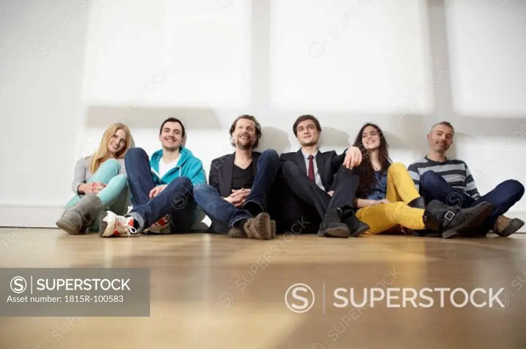 Germany, Cologne, Men and women sitting on floor