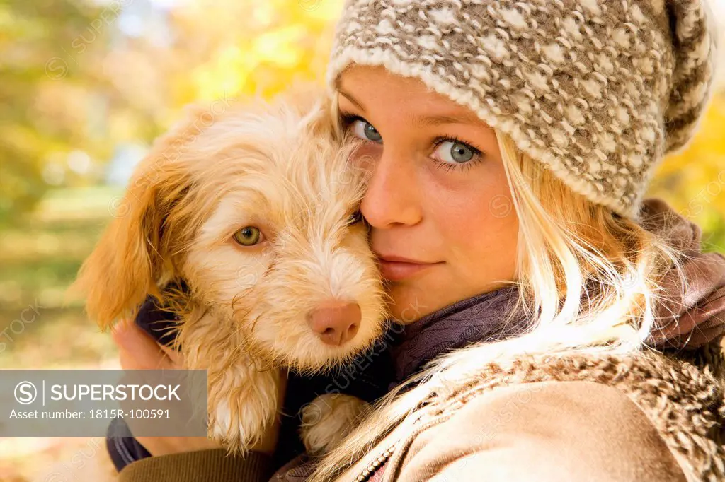 Austria, Young woman holding dog in autumn, portrait, close up