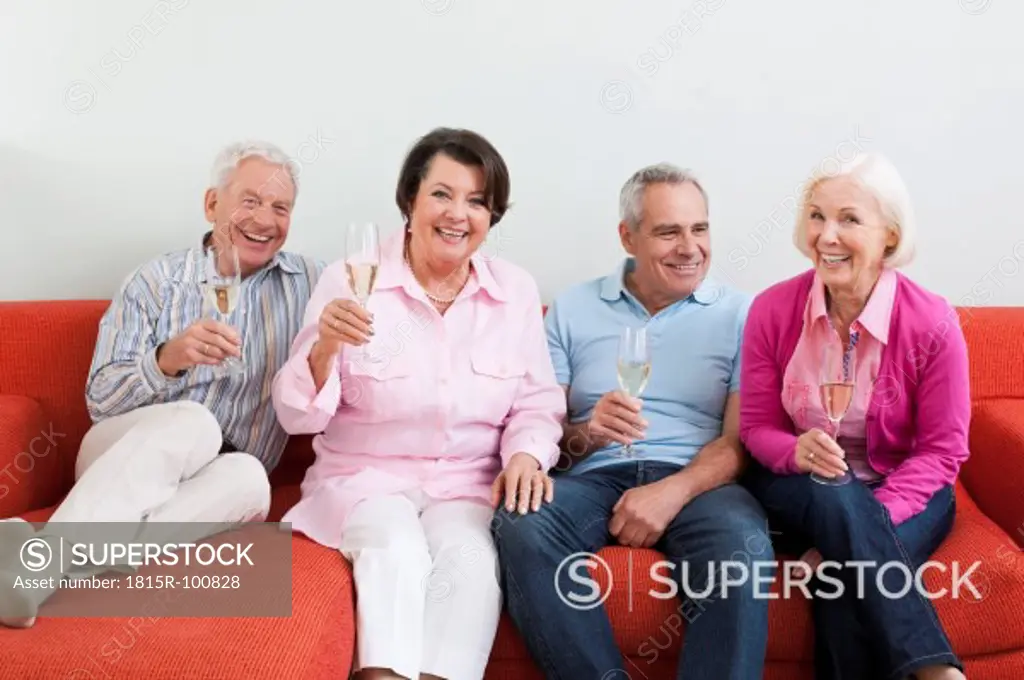 Germany, Leipzig, Senior men and women drinking sparkling wine, smiling