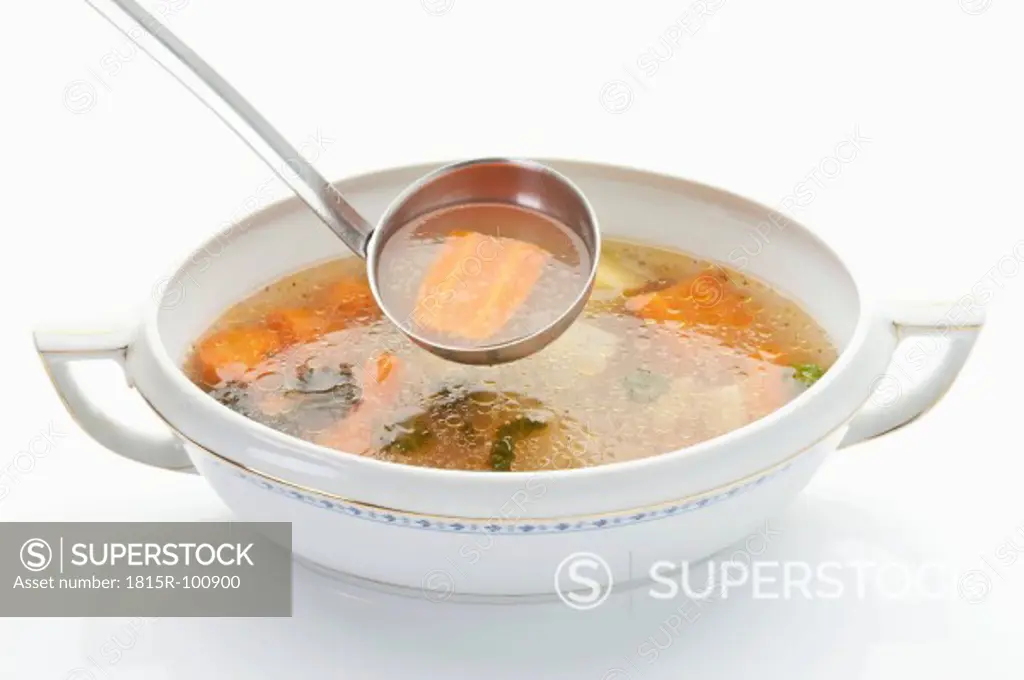 Chicken soup in tureen with dipper on white background