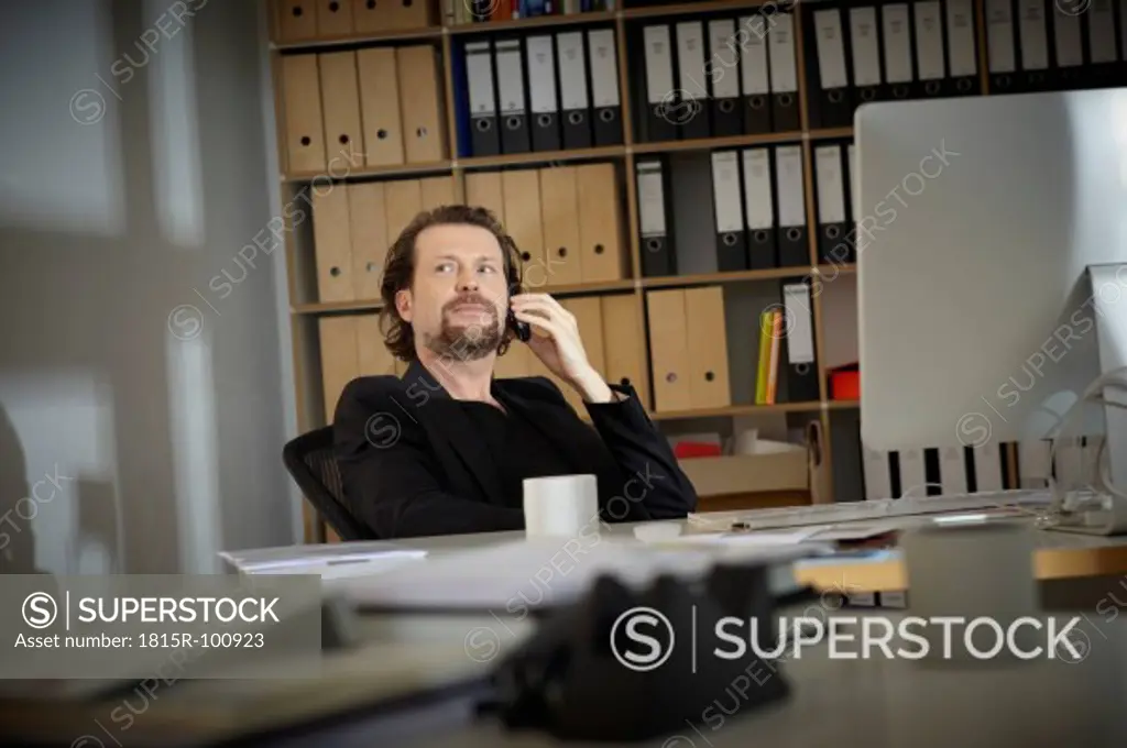 Germany, Cologne, Mature man on cell phone in office