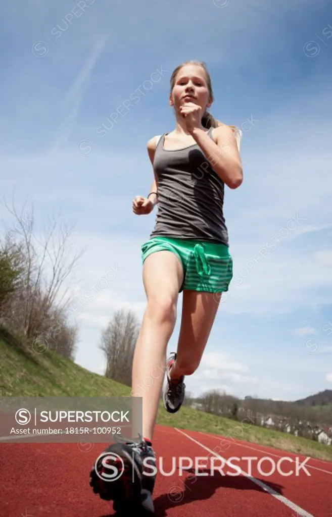 Austria, Teenage girl running on track, portrait